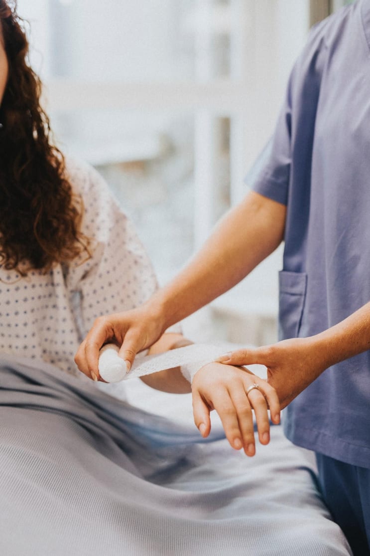 person rolling bandage on woman's left arm person rolling bandage on woman's left arm